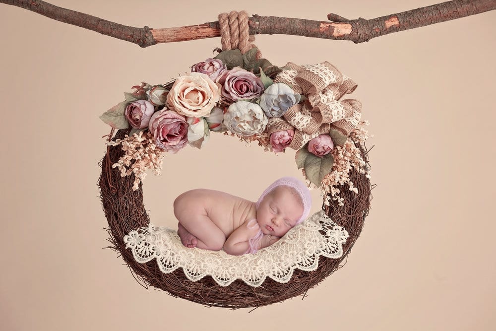 baby sleeping in a floral hoop swing