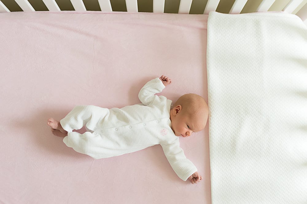 baby in white cloth lying in a crib