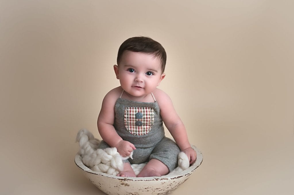 baby wearing gray jumper while holding a cotton